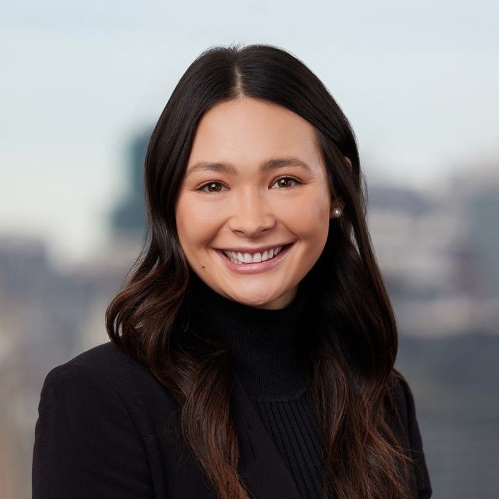 A woman in a black jacket and turtleneck smiles for the camera