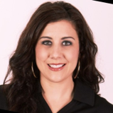 A woman wearing a black shirt and hoop earrings smiles for the camera.