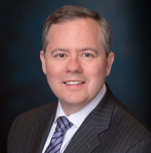 A man in a suit and tie is smiling for the camera