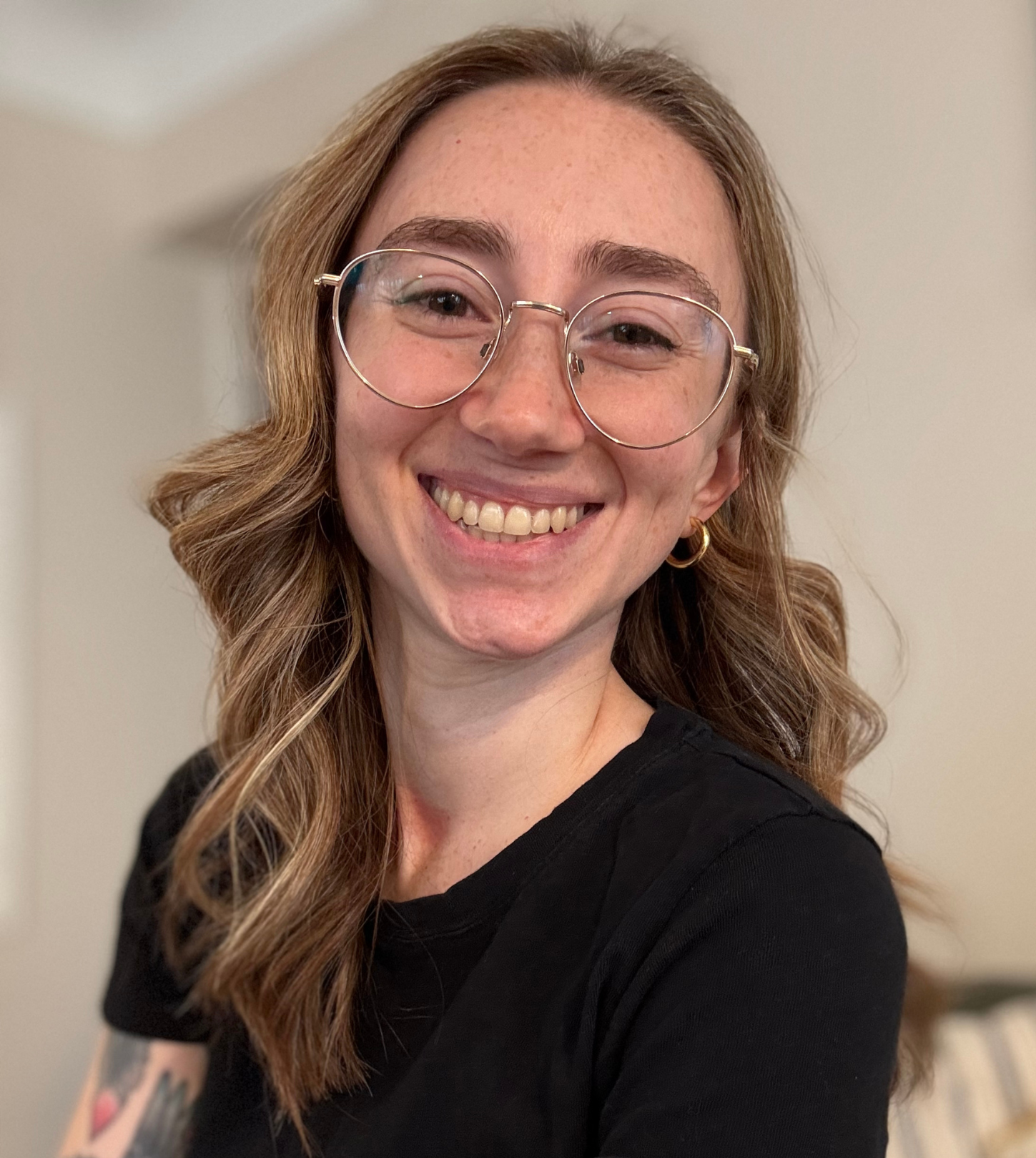 A woman wearing glasses and a black shirt is smiling for the camera.