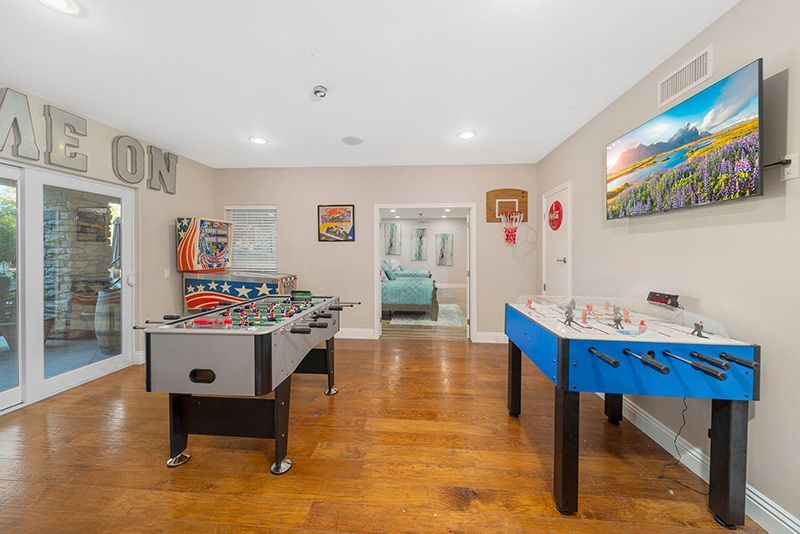 a game room with two pool tables and a basketball hoop