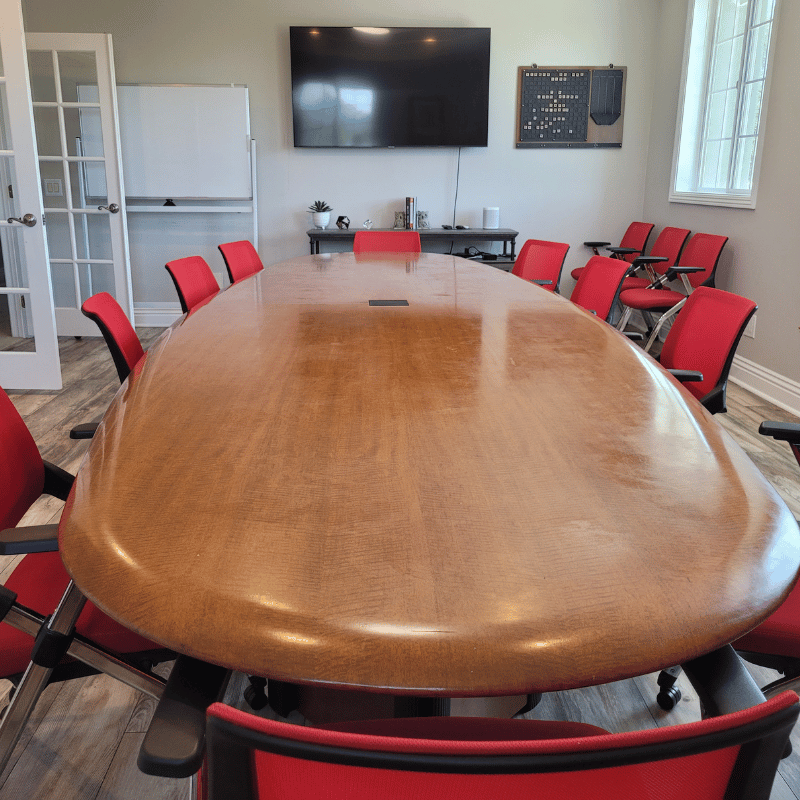 a conference room with a long wooden table and red chairs