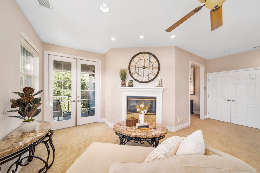 a living room with a fireplace, couch, table and ceiling fan
