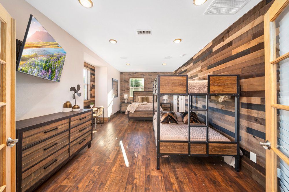a bedroom with bunk beds, a dresser, and a television