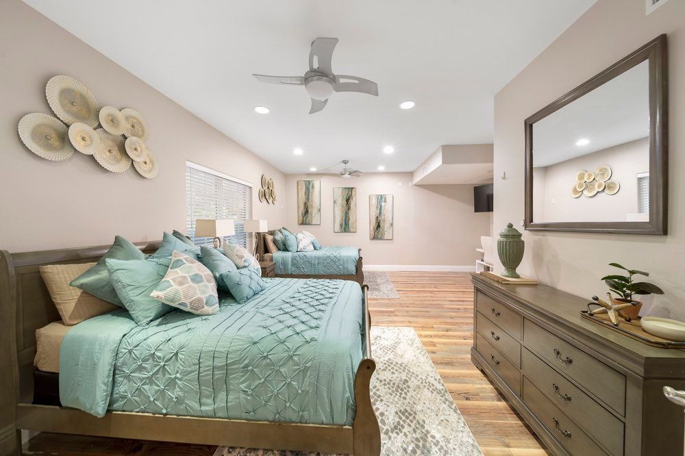 a bedroom with two beds, a dresser, a mirror and a ceiling fan