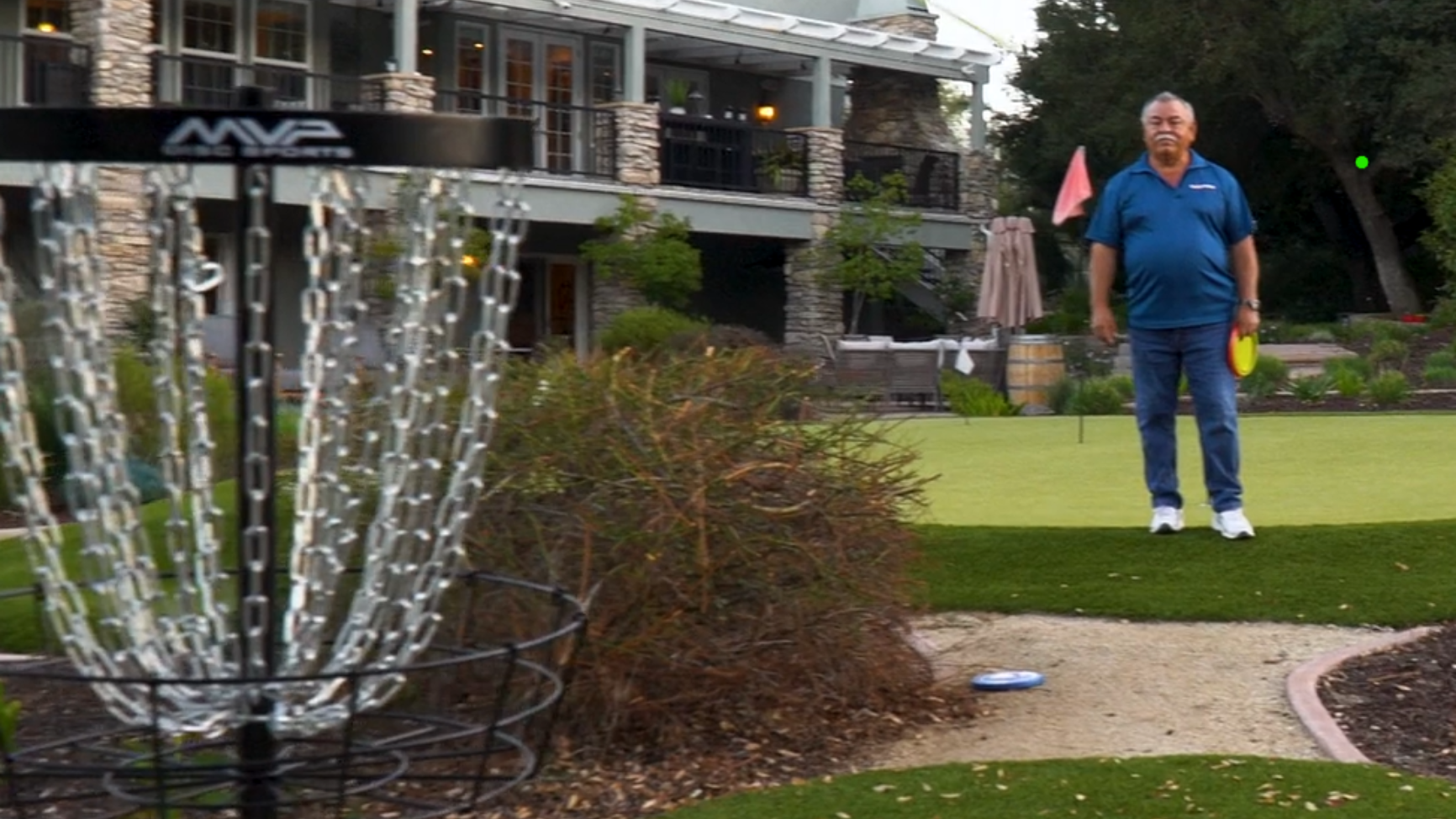 Man standing on a lawn near a large metal fountain in a park-like setting