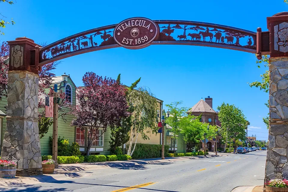 Decorative archway over a quiet street with trees and buildings on a sunny day