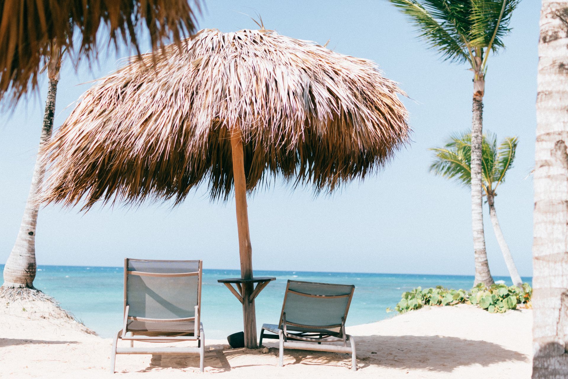 there are two chairs under an umbrella on the beach