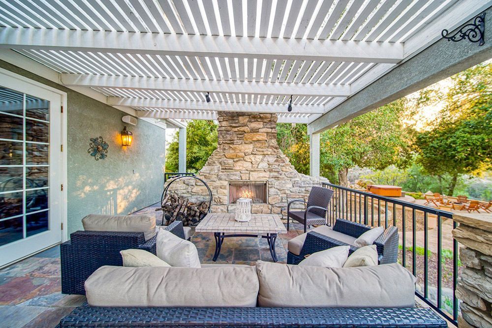 a patio with a couch , chairs , table and fireplace.