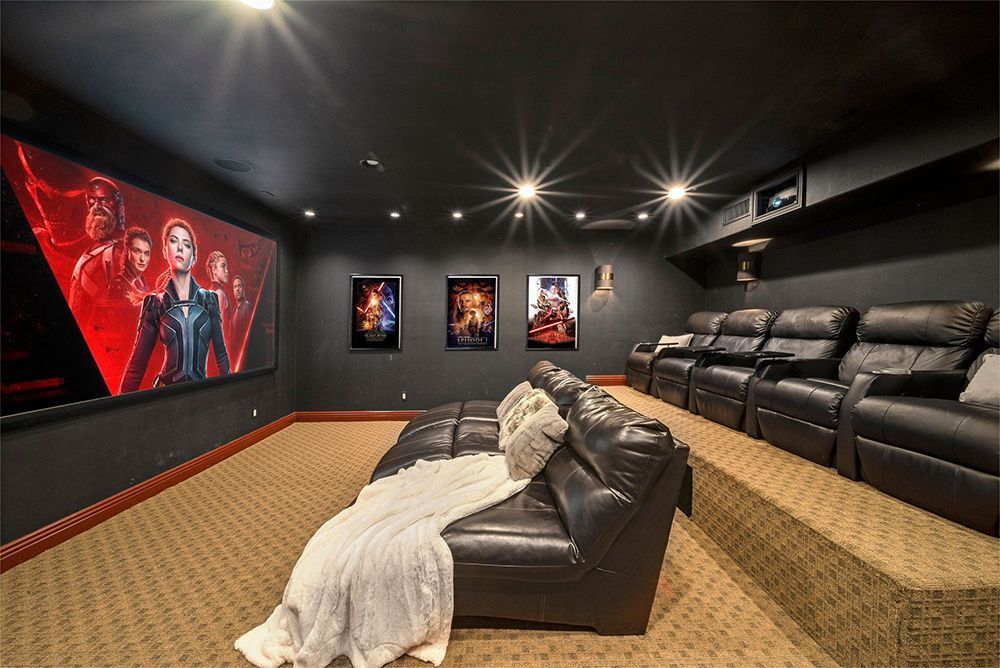 A home theater with a couch , chairs and a large screen.