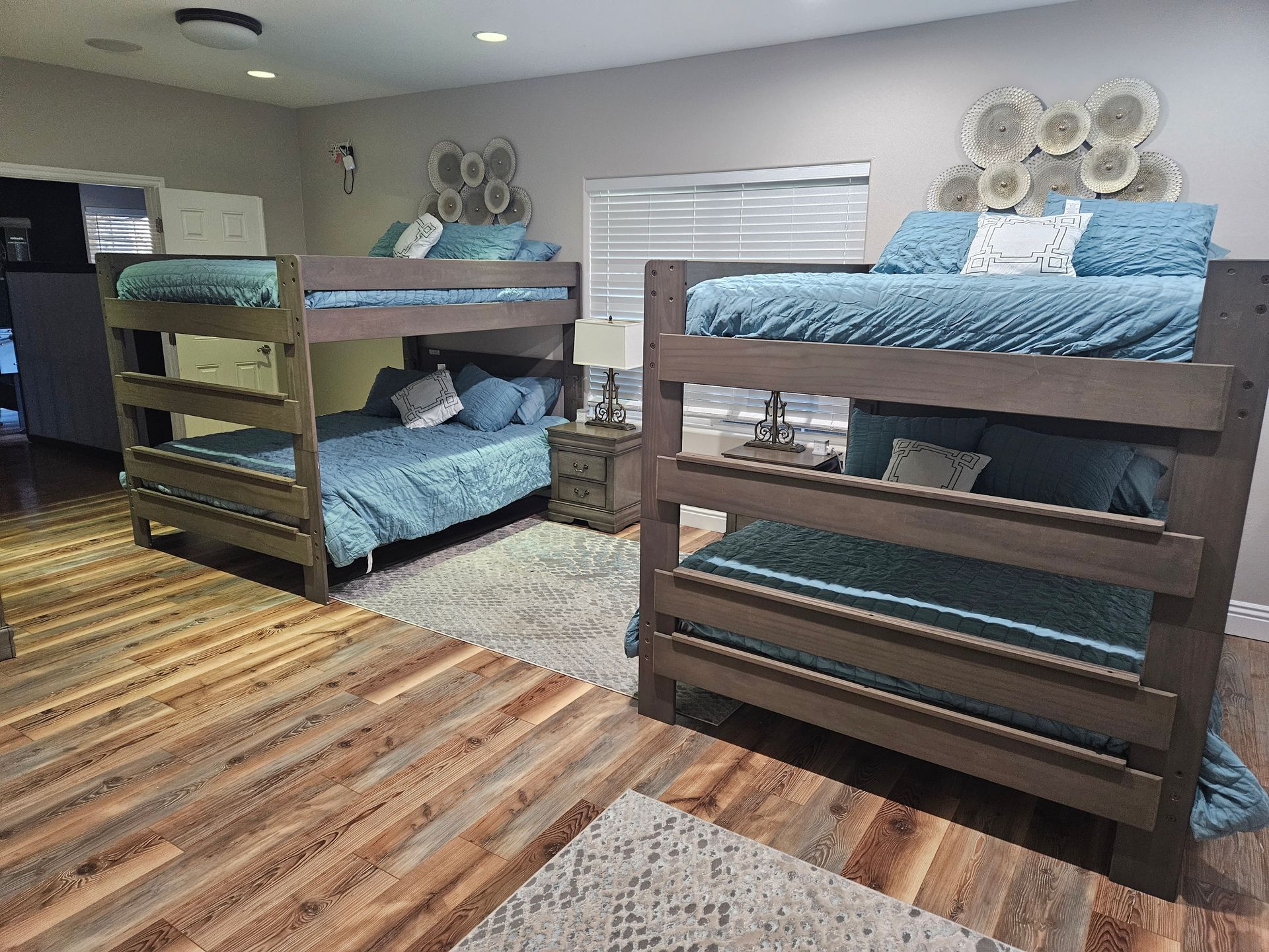 Dorm room with two bunk beds, striped rug, and gray walls in a small shared bedroom