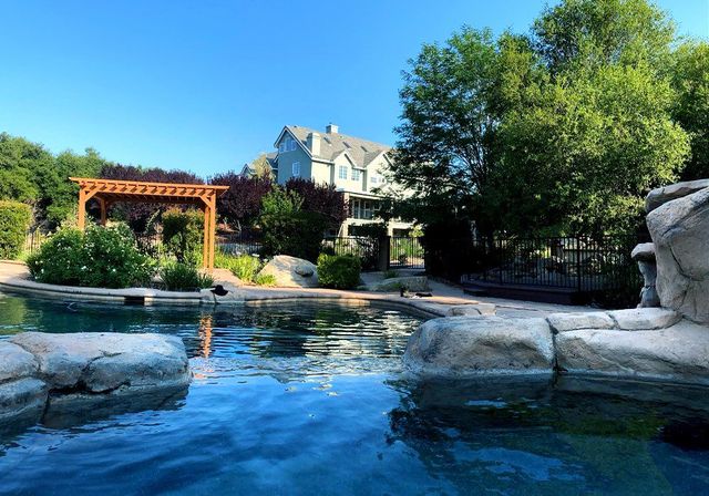 A large swimming pool with a house in the background