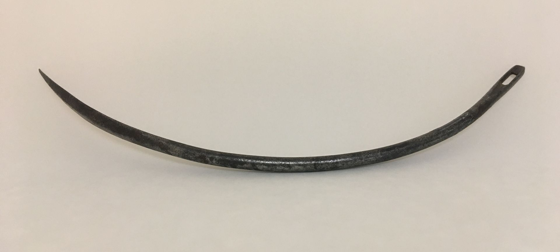 Curved black metal tool with a small looped handle on a white background