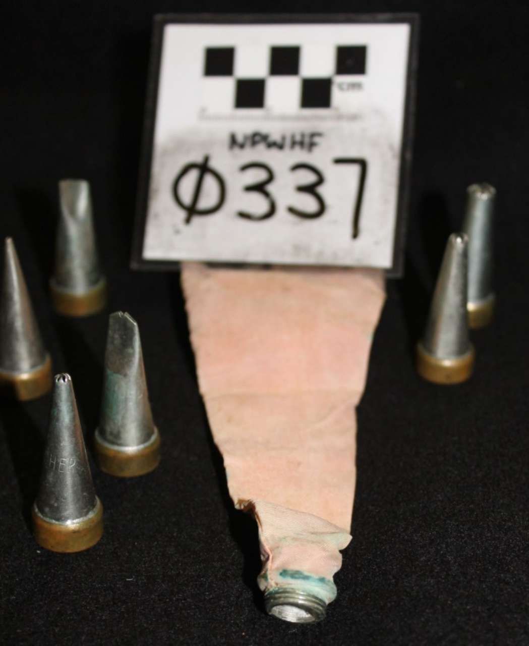 Spent bullet cartridges around a labeled evidence tag, with one cartridge centered in the foreground.