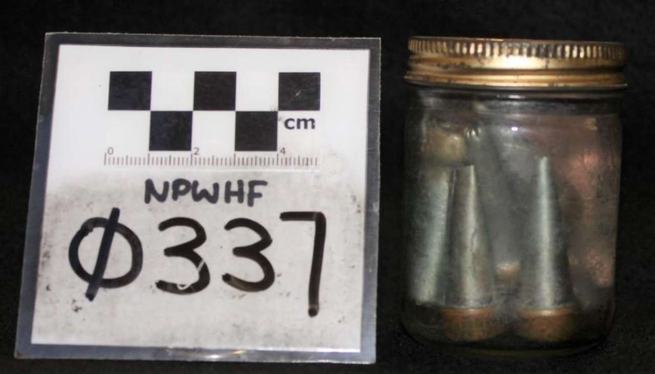 Small glass jar with metal lid beside a labeled scale card marked “NPWHF Ø337”.