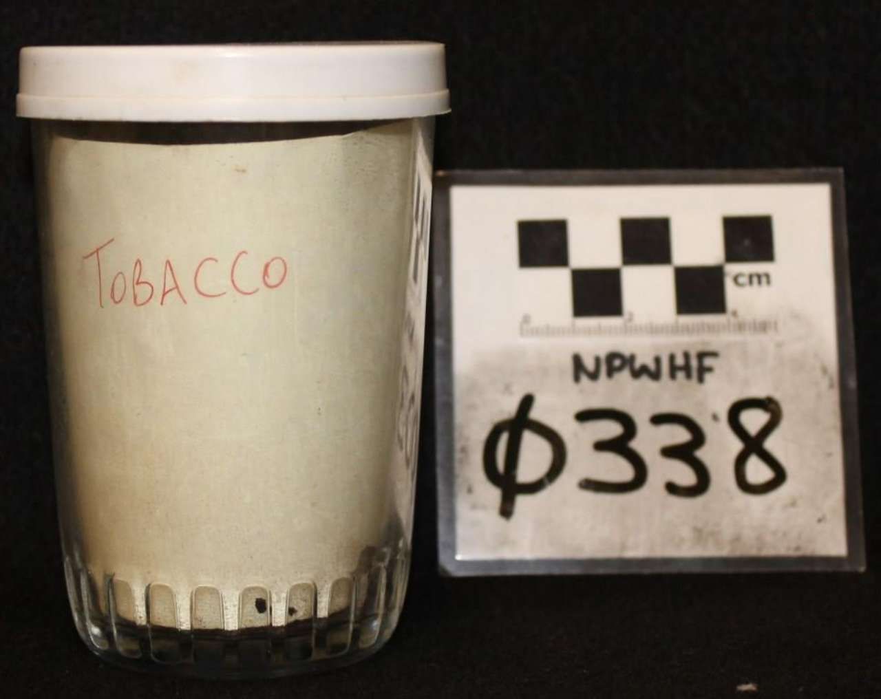 Glass jar labeled “TOBACCO” beside a scale card marked “NPWHF Φ338”.