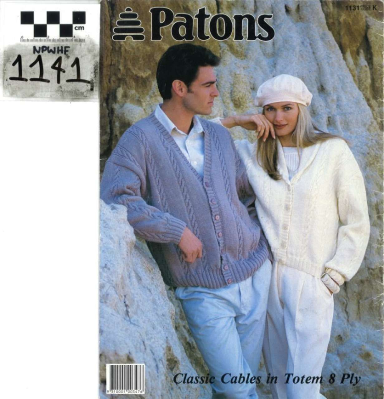 Two models wearing knitted sweaters and hats, leaning against a rock wall on a Patons yarn pattern cover