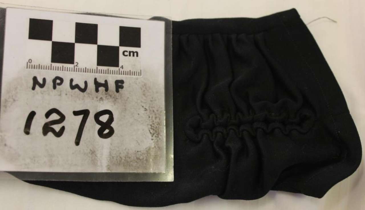 Black glove beside a measurement card labeled “NPWHF 1278” on a white background