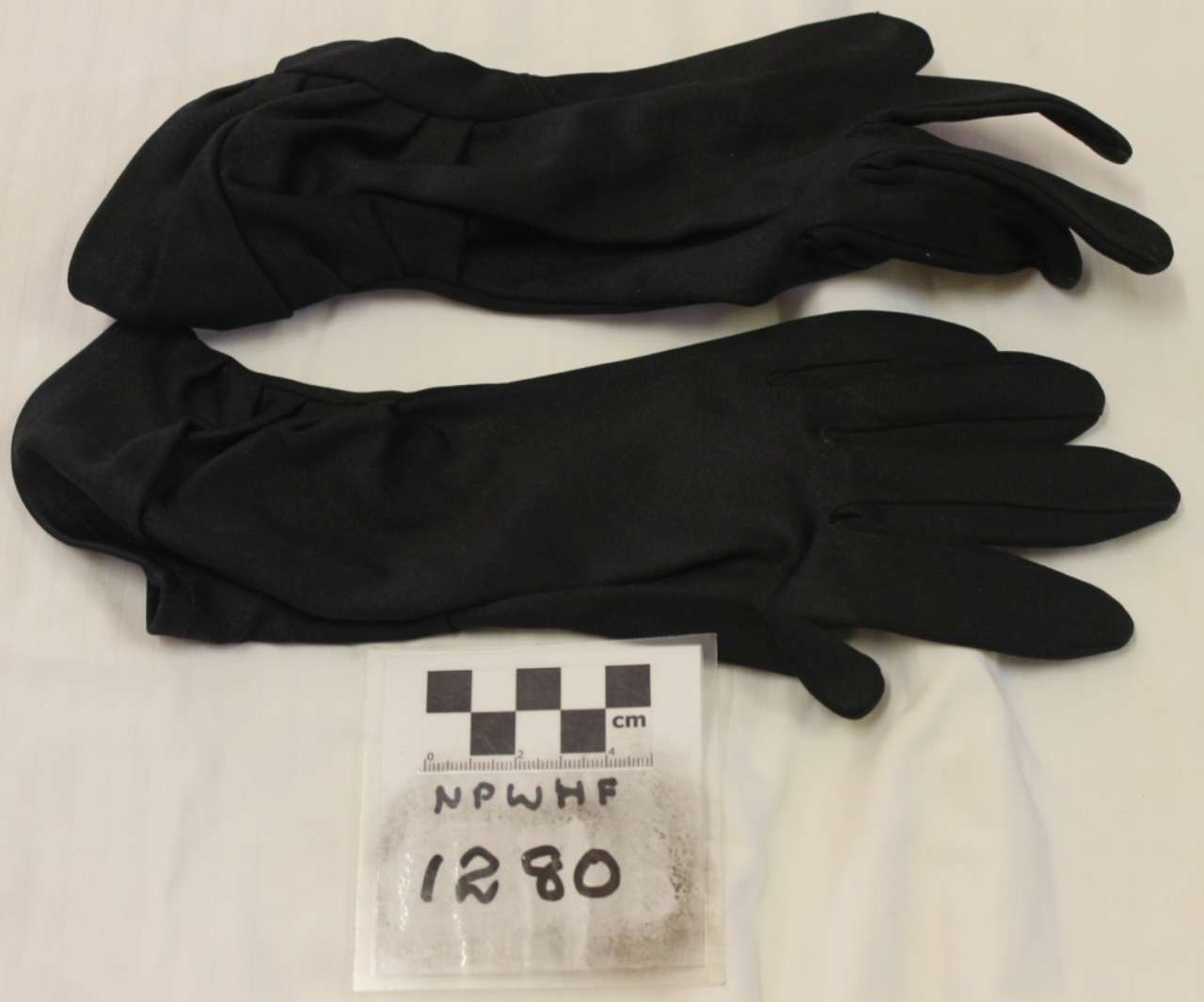 Pair of black gloves laid out above a small evidence label marked “1280.”
