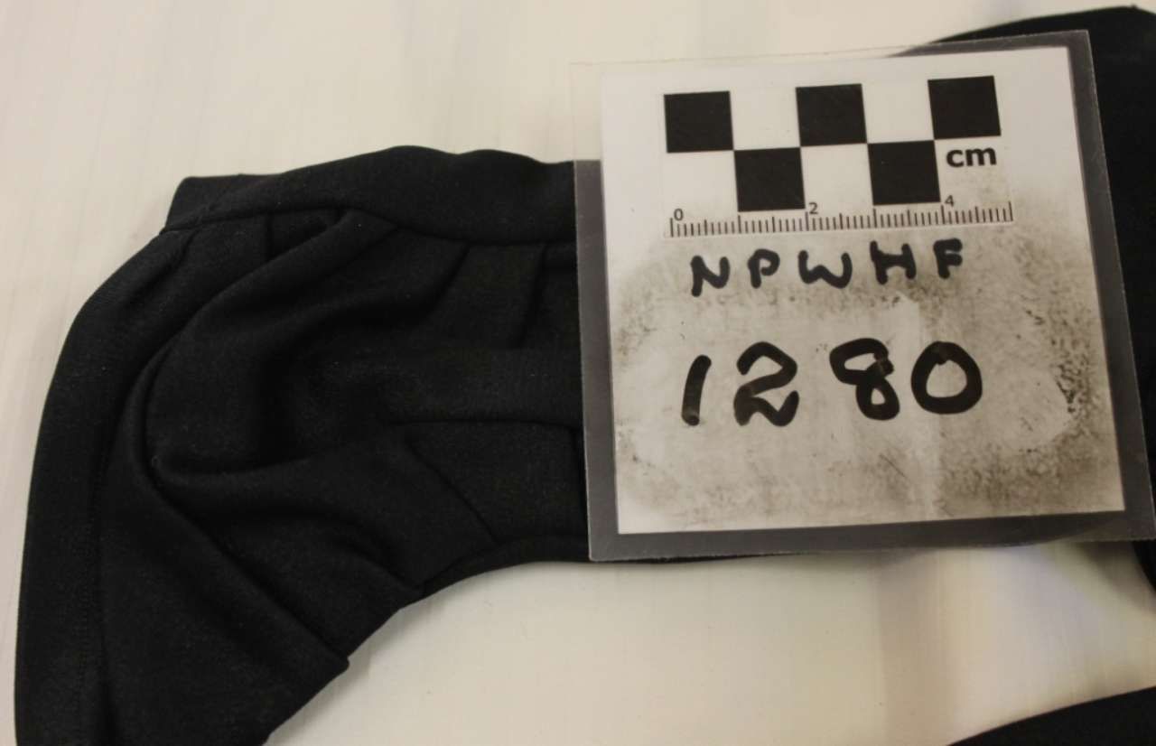 Black folded fabric beside a labeled measurement card marked “1280 cm”