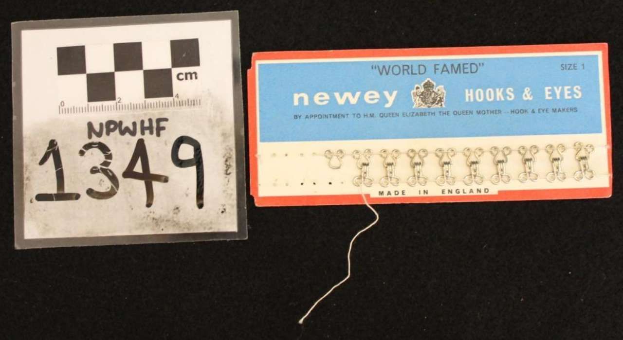 Race bib and blue Newey Hooks & Eyes package on black background