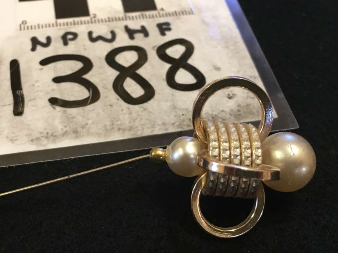 Silver beaded clasp or pendant on a cord, with a “1388” tag in the background