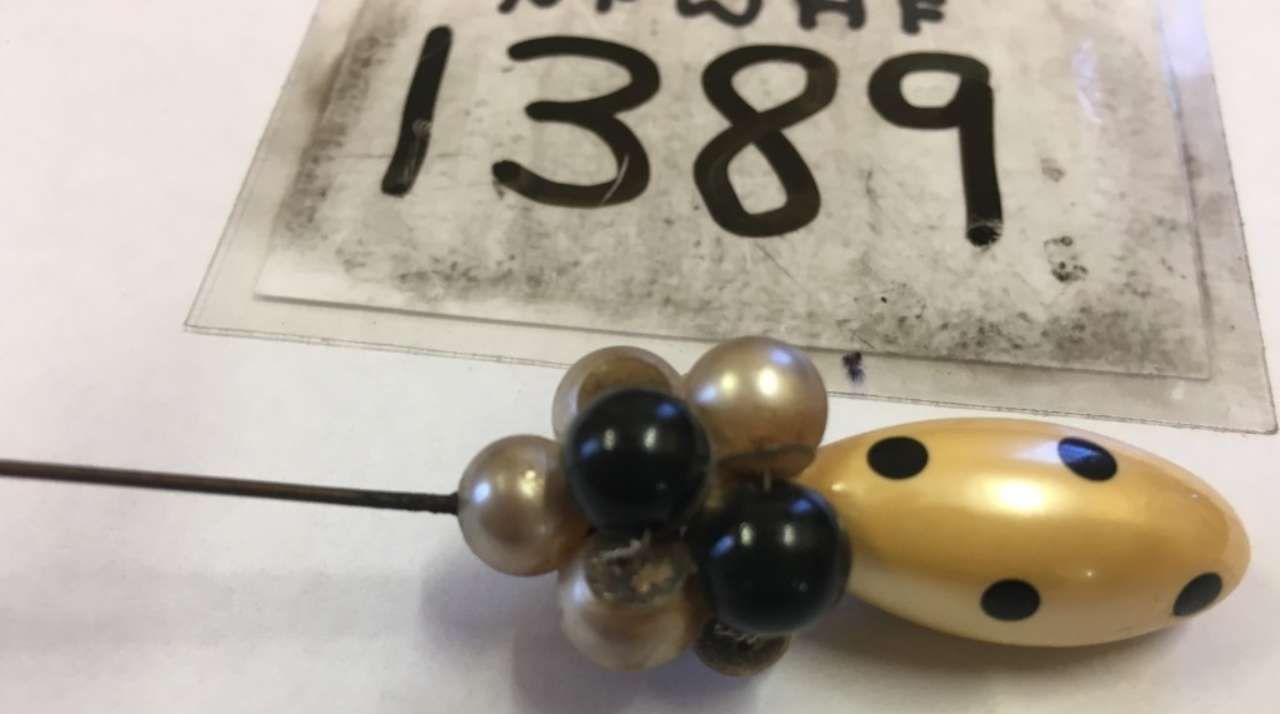 Beaded ladybug-shaped jewelry beside a paper labeled “1389”