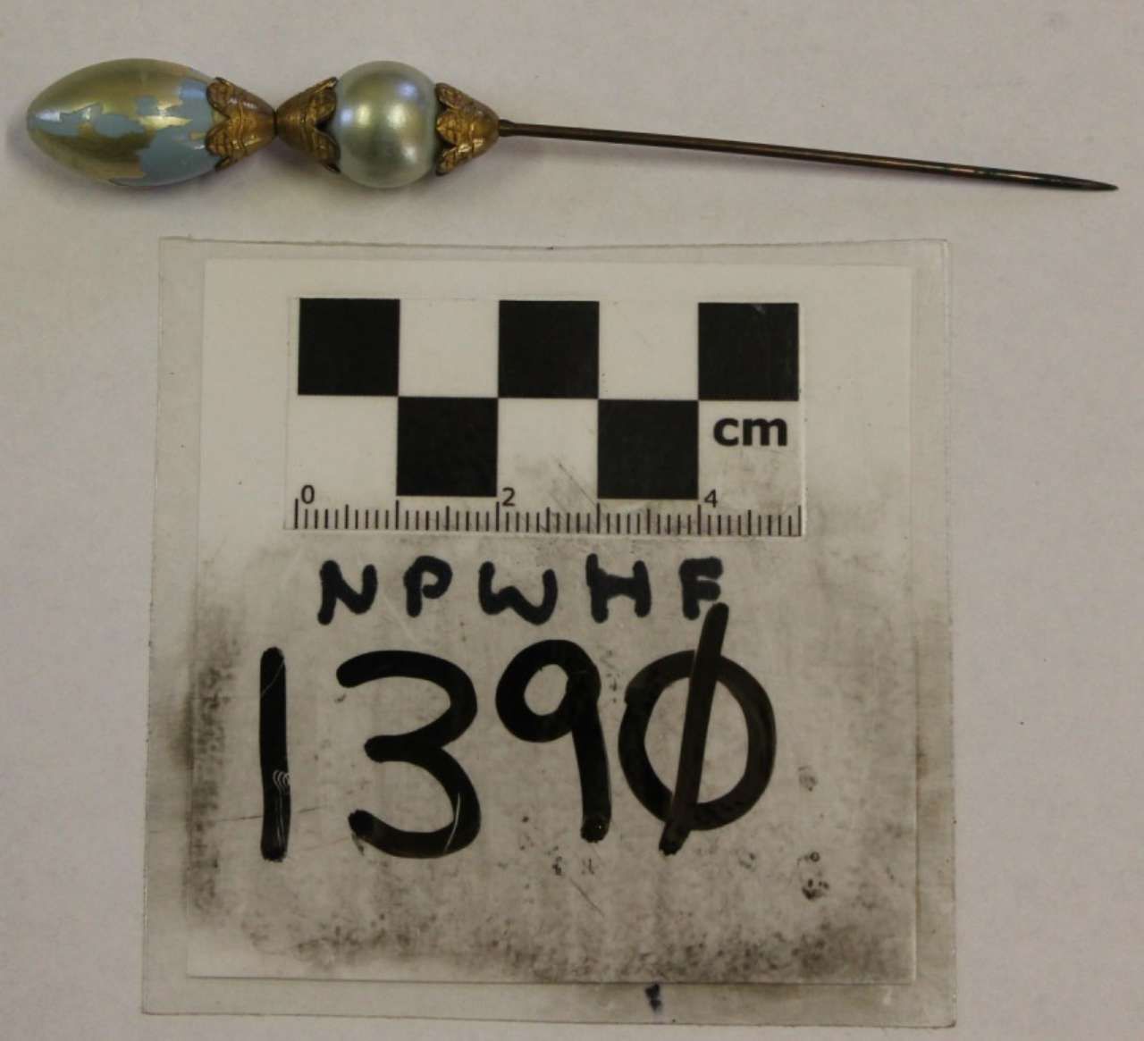 Small glass bead-ended metal pin on a measurement card with handwritten number 390.