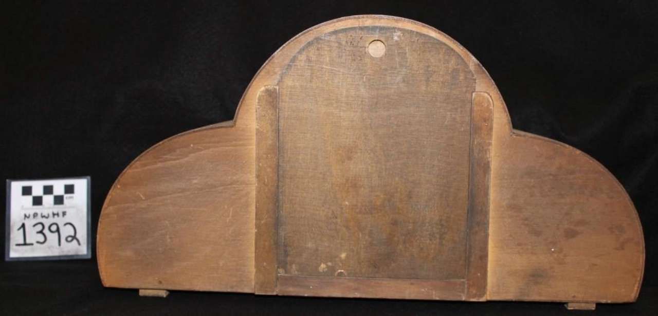 Wooden arched decorative panel with a central door-like section, shown against a black background.
