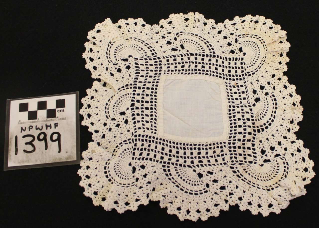 White crocheted lace square doily with scalloped edges beside a black-and-white label reading 1399