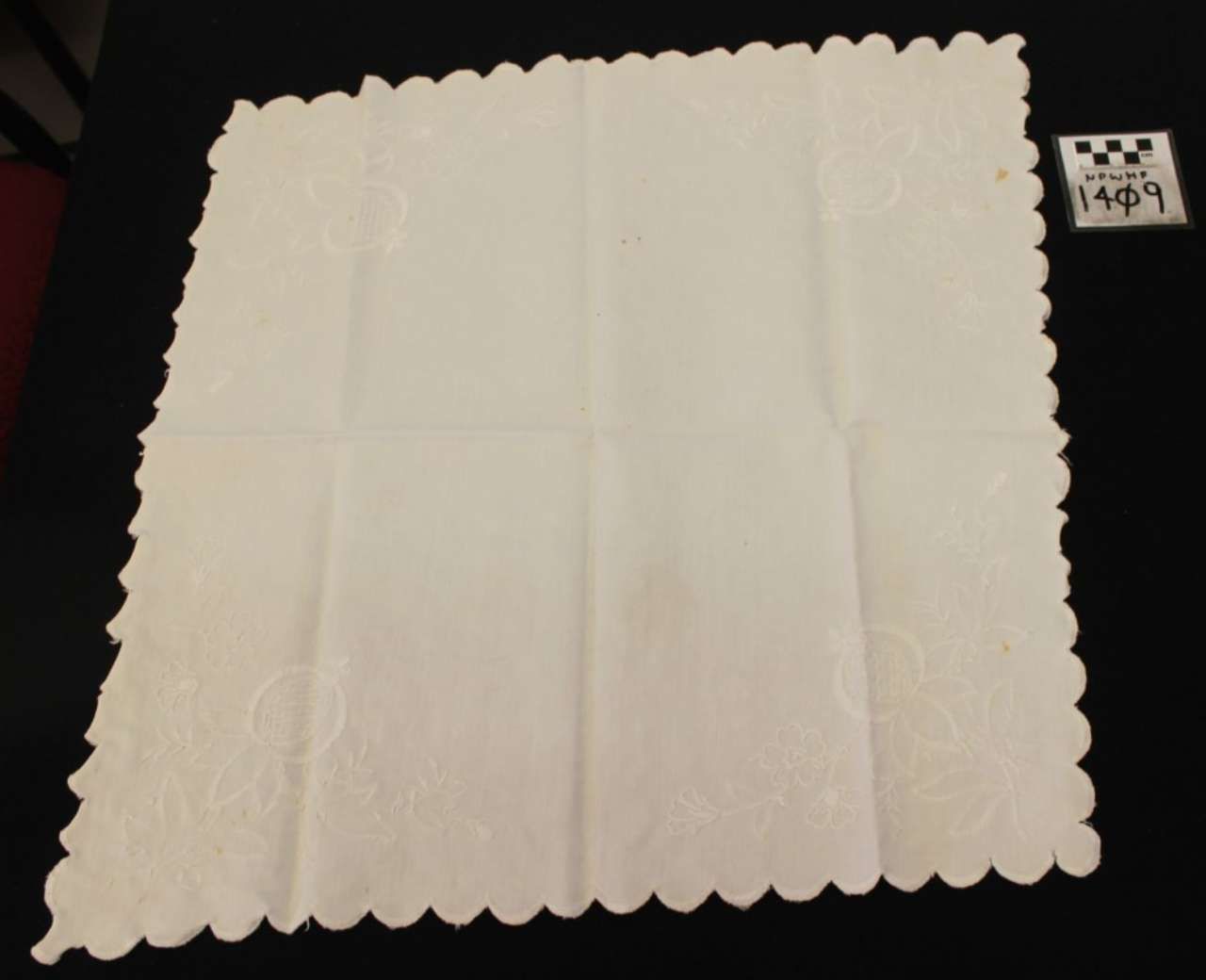 White scalloped paper doily or napkin on a dark surface, with a small price tag nearby.