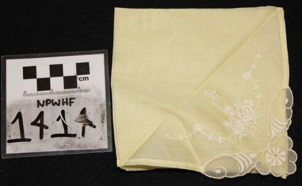 Yellow folded fabric with lace trim beside a black-and-white measurement scale label numbered 141.