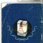 Small white product package on a blue fabric surface, with loose thread or cord around it.