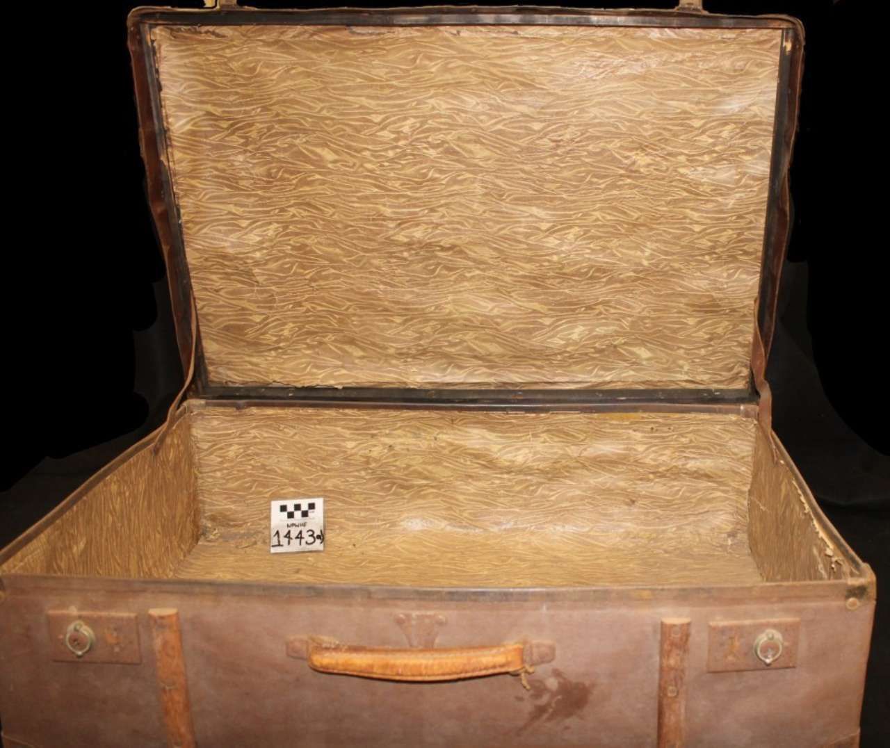 An open vintage suitcase with tan lining and worn brown leather exterior.