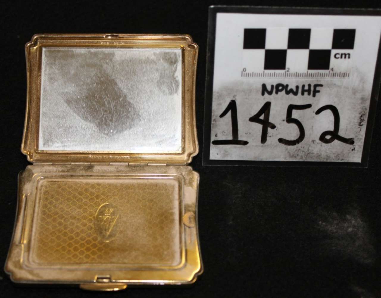 Open gold compact case beside a labeled evidence card on a black background