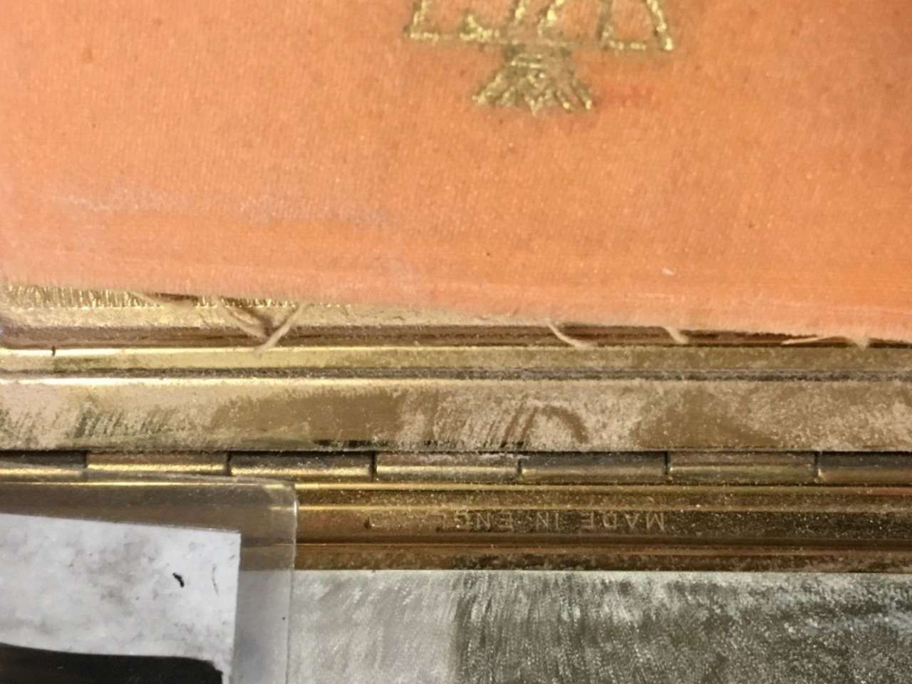 Close-up of an orange embossed book cover with a gold decorative emblem and worn edges
