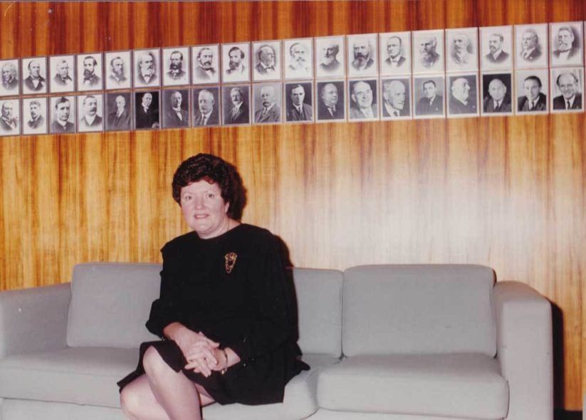 Person seated on a gray couch beneath a wall of framed black-and-white portraits.