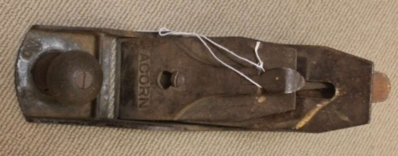 Close-up of a rusty metal hand plane tool on a plain background