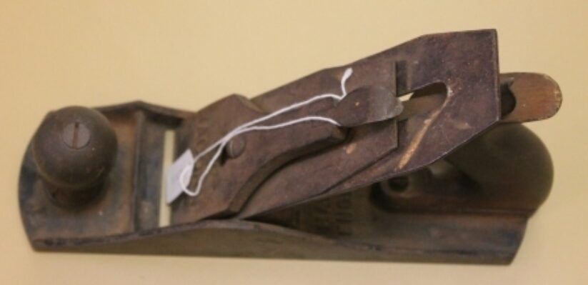 Antique metal hand plane with a dark wooden body and knob on a white background