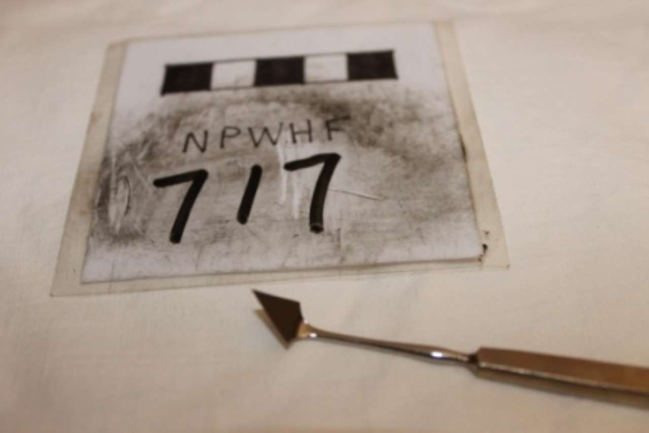 Vintage label card with handwritten numbers “717” and a metal pointer on a table