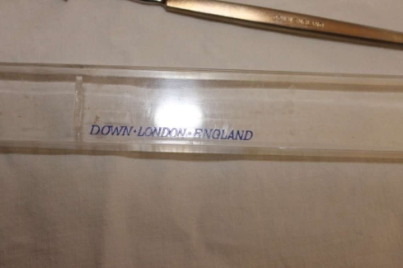 Label reading “Down-London-BY-Road” on a beige surface with a metal rod above it