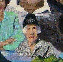 Person in a black cap and patterned shirt sitting among others, holding green flowers.