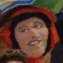 Close-up of a person in a red hood, looking sideways with a slight smile.