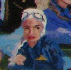 Child in blue jacket and swim goggles, looking at the camera