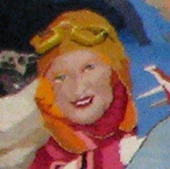 Close-up of a smiling person in a yellow hat and orange scarf against a blue background