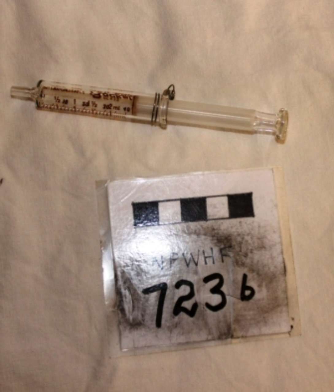 Used syringe next to a small labeled evidence bag marked 7236.