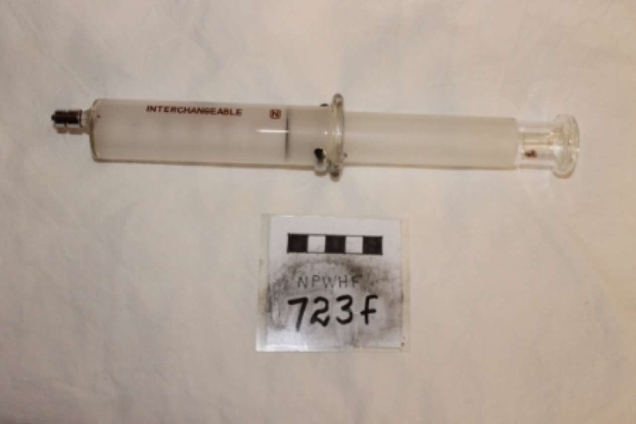 Clear plastic syringe next to a small label reading “723F” on a white background