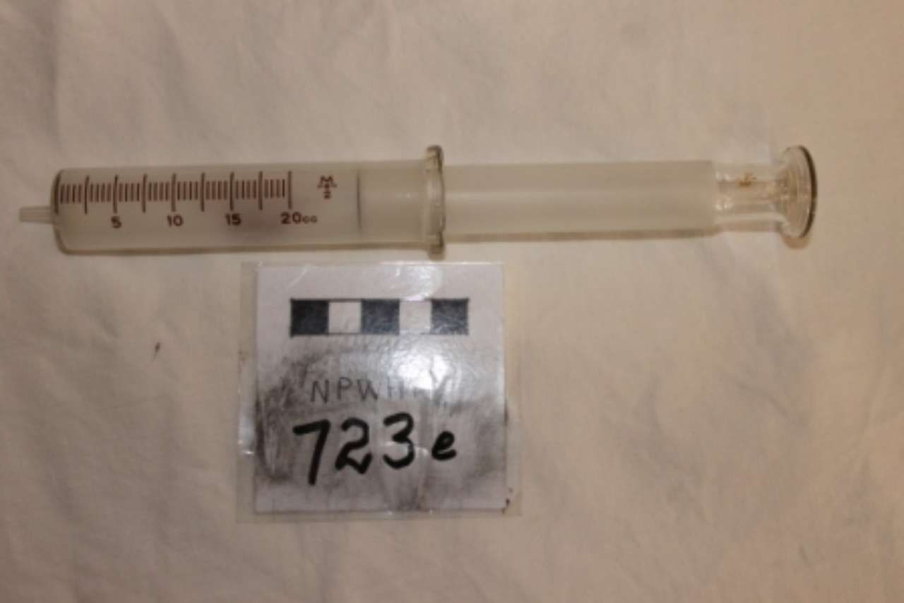 Clear plastic syringe with measurement markings and a handwritten label reading 7236 on a white background
