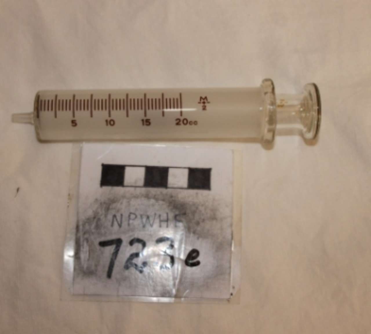 A syringe and a small labeled evidence bag on a plain surface