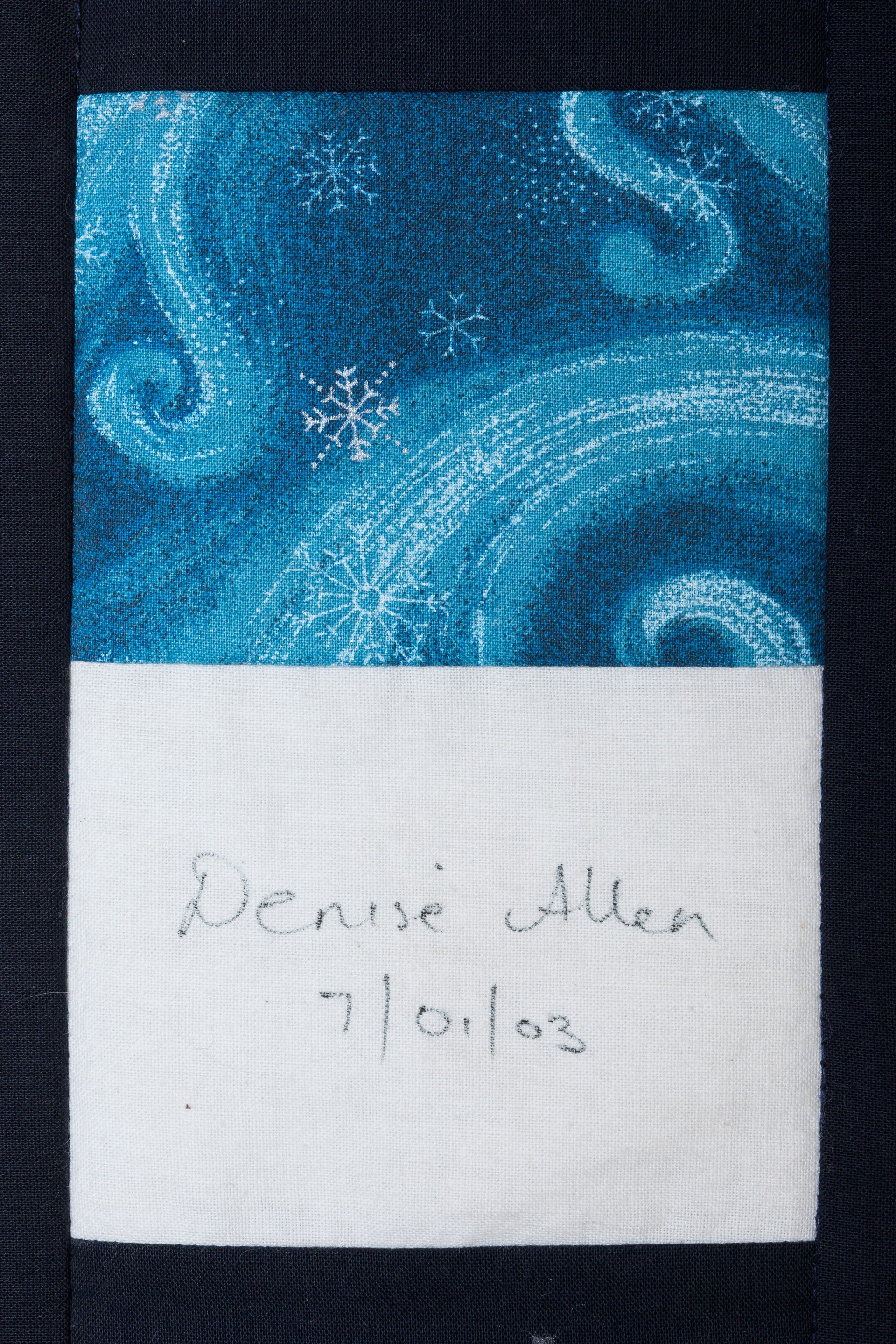 Blue patterned fabric label with handwritten name and date on white section